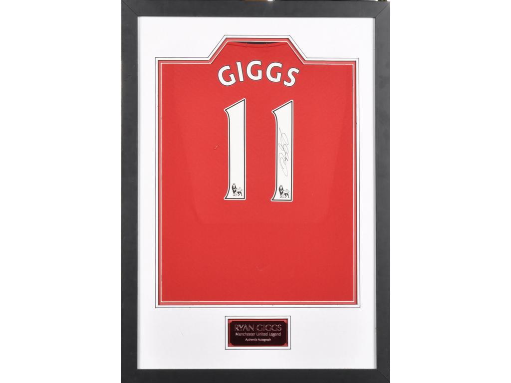Partie de maillot de football du joueur Ryan GIGGS, joueur à Manchester United, avec dédicace. (un accroc au milieu). Dim. du cadre : 86x61 cm.