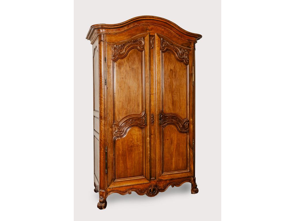 Belle armoire provençale en noyer. Corniche cintrée (à restaurer) reposant sur des montants arrondis et deux petits pieds antérieurs à enroulements reliés par une traverse ajourée d'une coquille. Elle ouvre par deux portes sculptées de feuillages et motifs de rocailles. Epoque XVIIIème siècle. (Fentes et manques au pied droit). Dim : 257 x 157 x 70 cm.