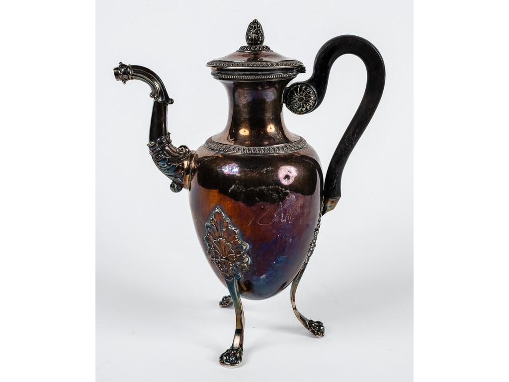 Verseuse en argent (Poinçon Minerve) de style Empire à décor de feuillages reposant sur trois pieds griffes. Manche en bois. (Absence probable du bec verseur). Poids brut : 593 gr. Hauteur : 27 cm.