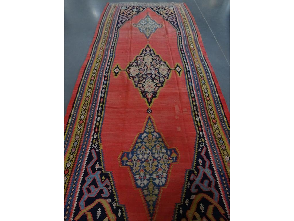 KILIM : Grand tapis galerie à décor de trois médaillons sur fond orangé (reprise, restaurations et quelques trous). Dim : 420 x 170 cm.