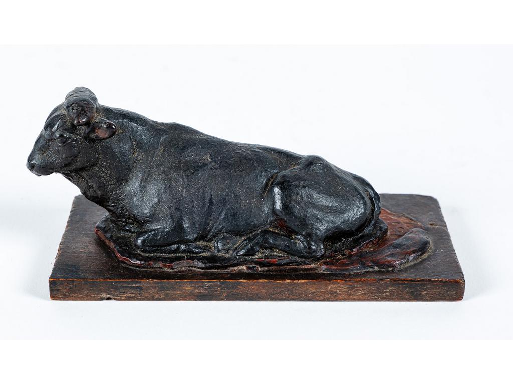 Sculpture en cire patiné figurant une vache couchée reposant sur un socle en bois. . Epoque XIXème siècle. Dim : 6 x 12.5 x 5 cm.