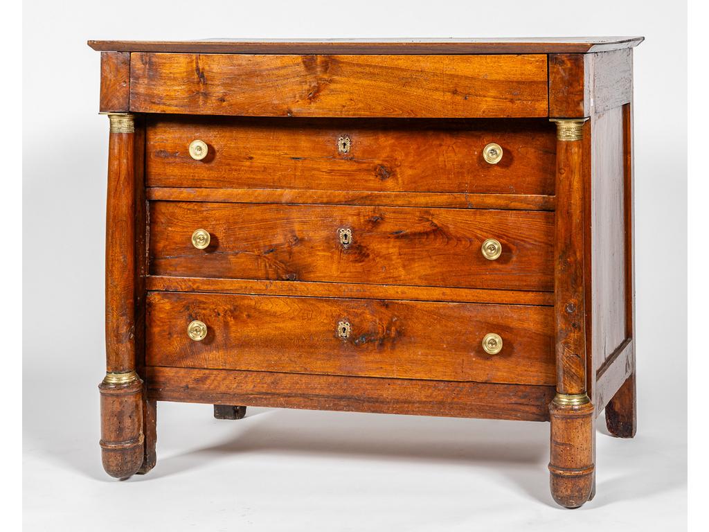 Commode d'époque Empire en noyer et placage de noyer ouvrant par quatre tiroirs en façade, encadrés de montant en forme de colonnes baguées. (Trous de xylophages, fentes et tâches). Dim : 96.5 x 115 x 62 cm.