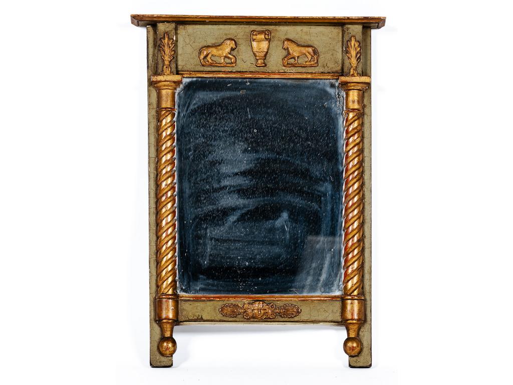 Petit miroir dans un encadrement en bois laqué et doré flanqué de demi-colonnes torsadées avec un linteau orné de lions. Epoque Restauration. Dim : 59 x 38 cm.