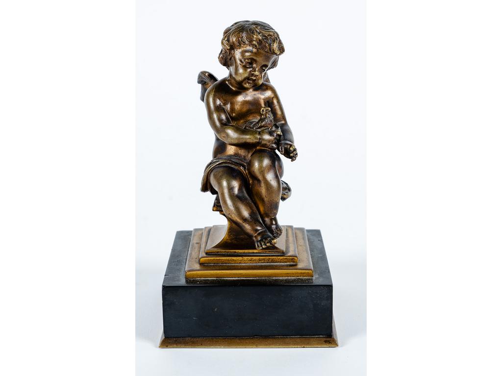 Petit sujet en bronze patiné représentant un angelot assis tenant un oiseau. Socle en marbre noir. (Petits éclats). Dim : 17 x 9 x 8.5 cm.