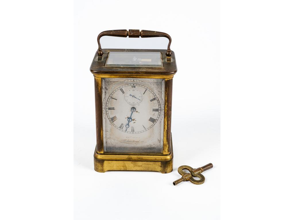 Charles OUDIN, Palais Royal : Petite pendulette de voyage en laiton doré et verre biseauté. Cadran en métal laqué à chiffres arabes avec cadran des secondes à 12 heures. (Mécanisme à réviser, usures à la dorure et éclats au cadran. Avec sa clé.) Dim : 12 x 9 x 8.5 cm.