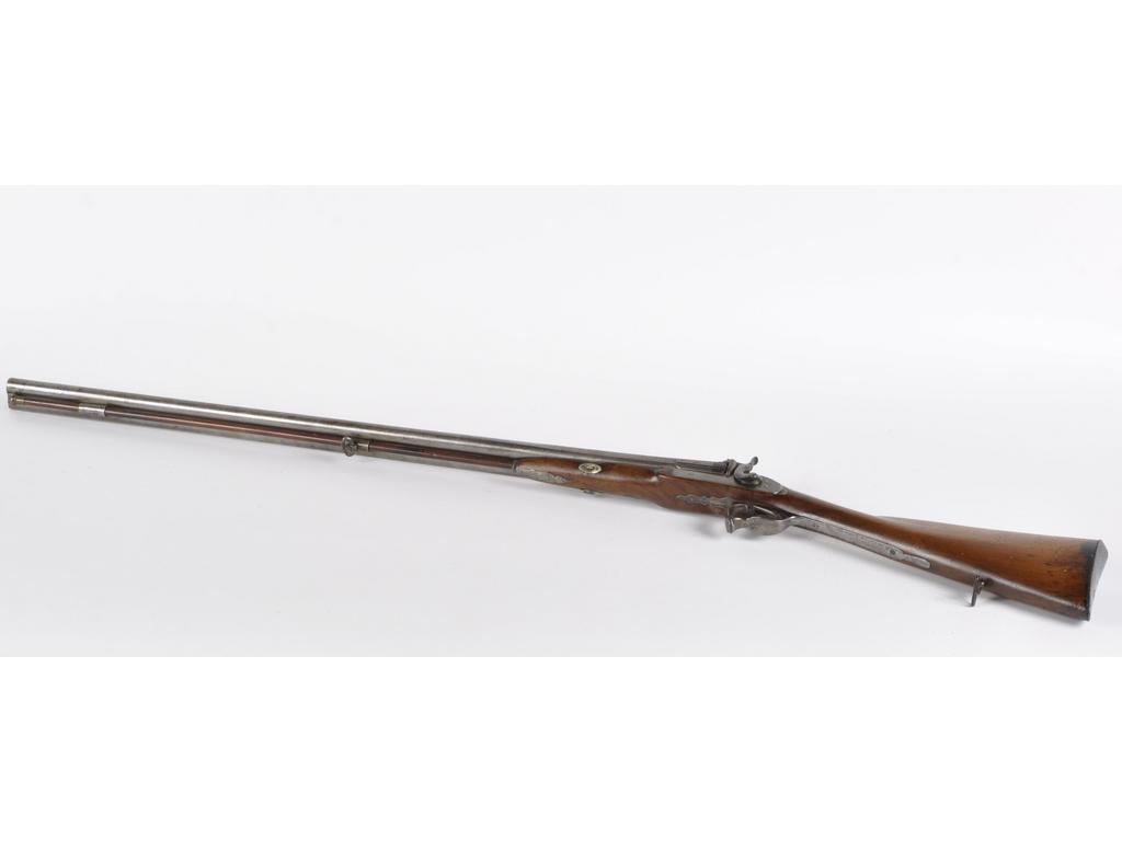 Fusil de chasse à percussion, deux coups. Canons ronds, à pans au tonnerre. Platine avant et chiens gravés de rinceaux. Garnitures en fer découpé, gravé en suite. Crosse en noyer (trous d'insectes). Baguette en bois à embout en laiton. Longueur : 122cm. A.B.E. Vers 1840.