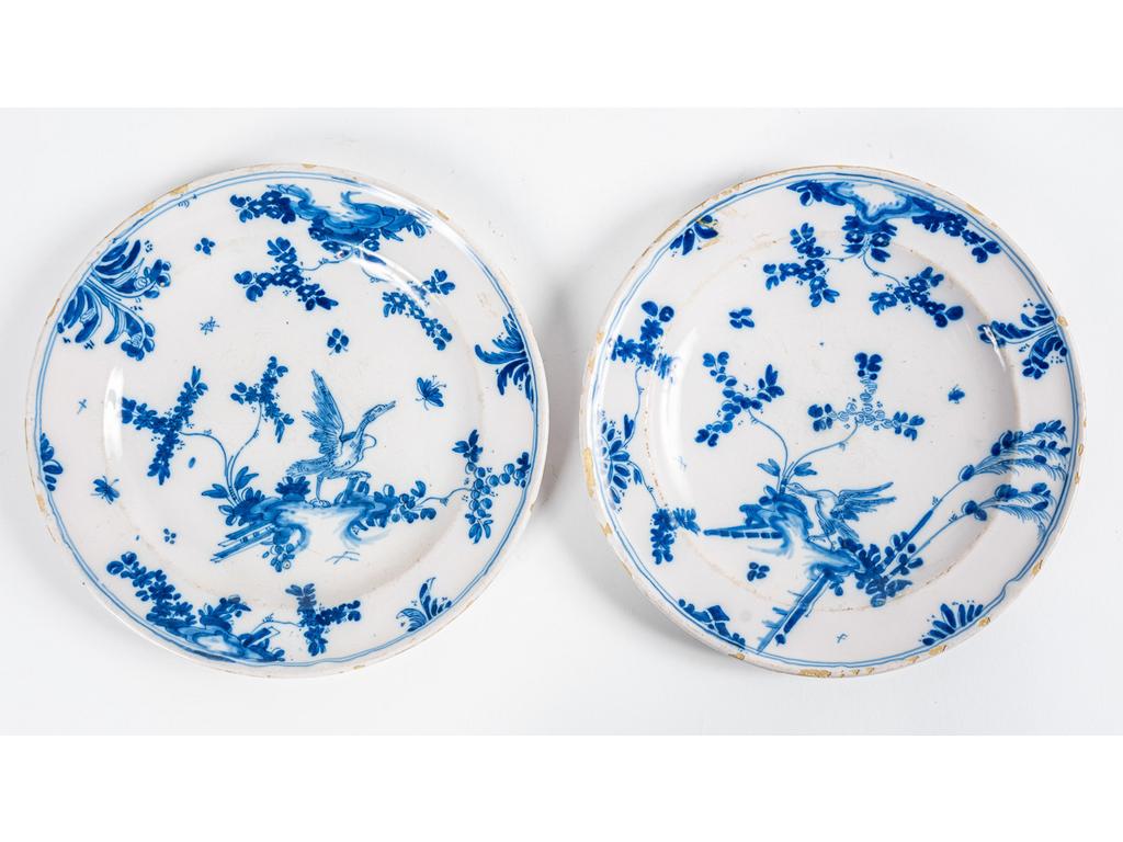 MARSEILLE, Fabrique de Leroy : Paire d'assiettes en faïence uniformément rondes à décor en camaïeu bleu d'un échassier et de végétations. Epoque XVIIIème siècle. (Eclats d'émail). Diamètre : 23.5 cm.