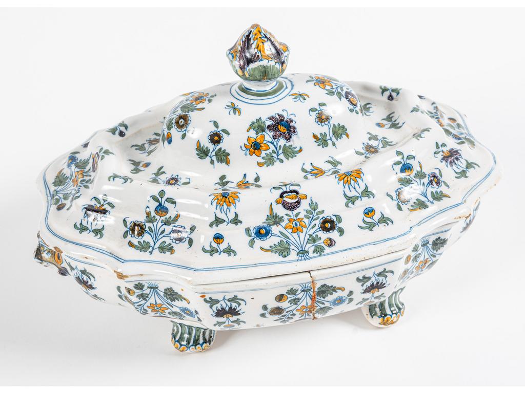 MOUSTIERS : Soupière en faïence à décor peint de fleurs de solanacées, le bassin orné de mufles de lions. Epoque XVIIIème siècle. (Bassin cassé, recollé et agrafé). Longueur : 30 cm.