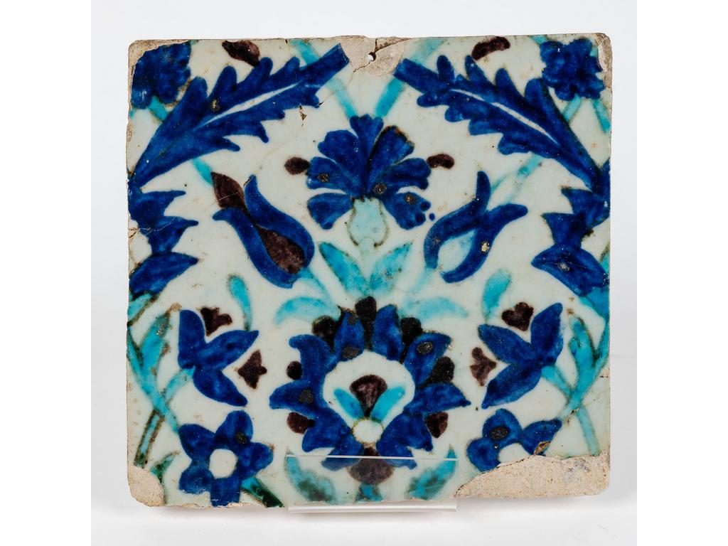 Carreau de parement en céramique siliceuse à décor polychrome émaillé de fleurs dans le goût d'IZNIK. (Accidents et manques). Dim : 21.5 x 22.5 cm.