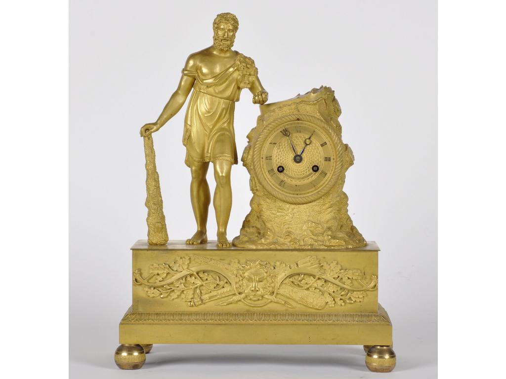 Pendule d'époque Restauration en bronze et métal doré représentant Hercule accoudé à une souche. Cadran signé DUFLOS à Paris. (Sans balancier, mouvement à restaurer). Hauteur : 39 cm.