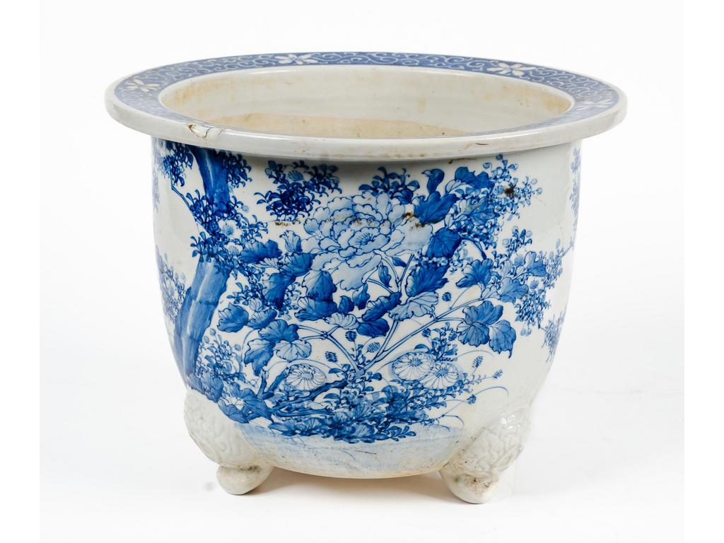 CHINE : Cache-pot tripode en porcelaine à décor bleu et blanc de fleurs. Vers 1900. (Restaurations). Hauteur : 26.5 cm. Diamètre : 34.5 cm.