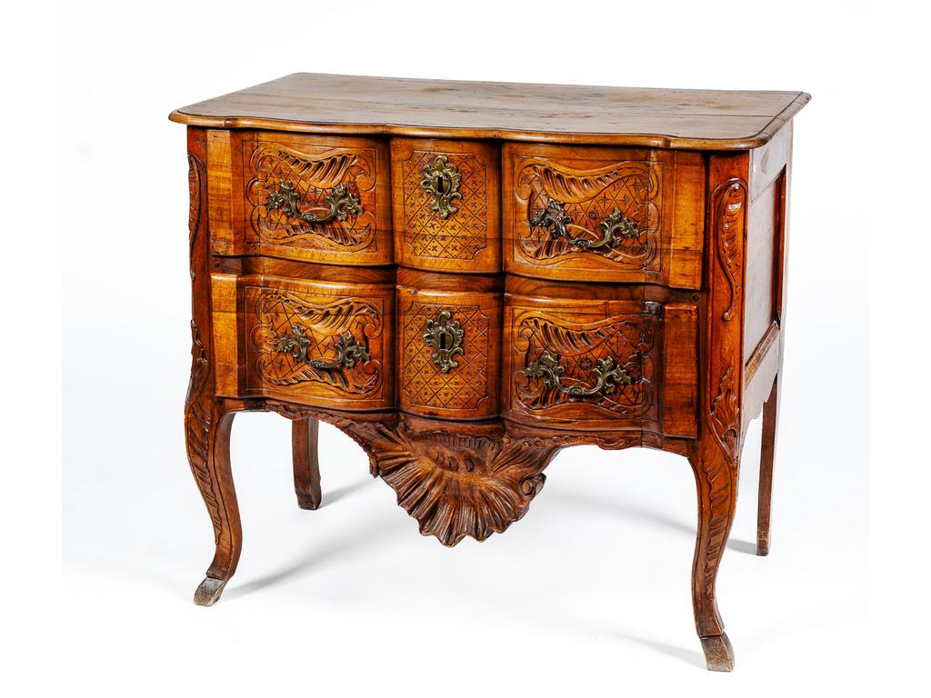 Petite commode de style Louis XV en noyer. Façade arbalète ouvrant par deux tiroirs. Décor sculpté de rocailles, treillages et d'une large coquille tombante sur la traverse. (Plateau avec tâches et brûlures. Sans clé). Dim : 88 x 101 x 59 cm.