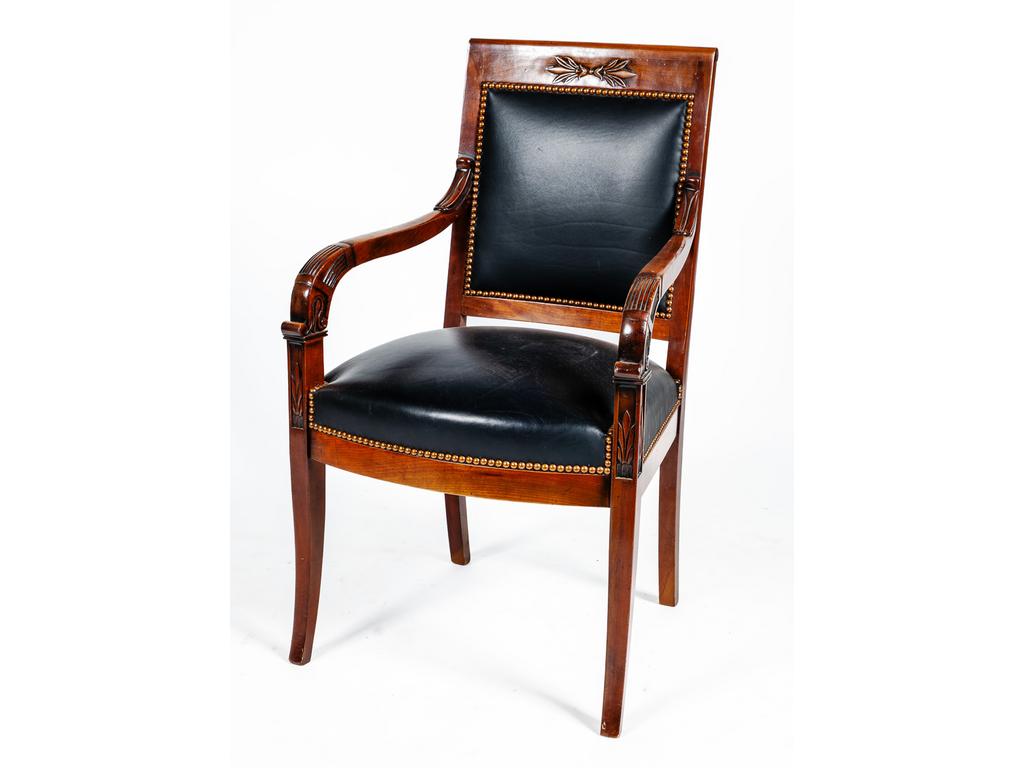 Fauteuil de style Empire en acajou et placage d'acajou à décor de volutes et feuillages reposant sur un piétement sabre. Epoque XXème siècle. Garniture de cuir.