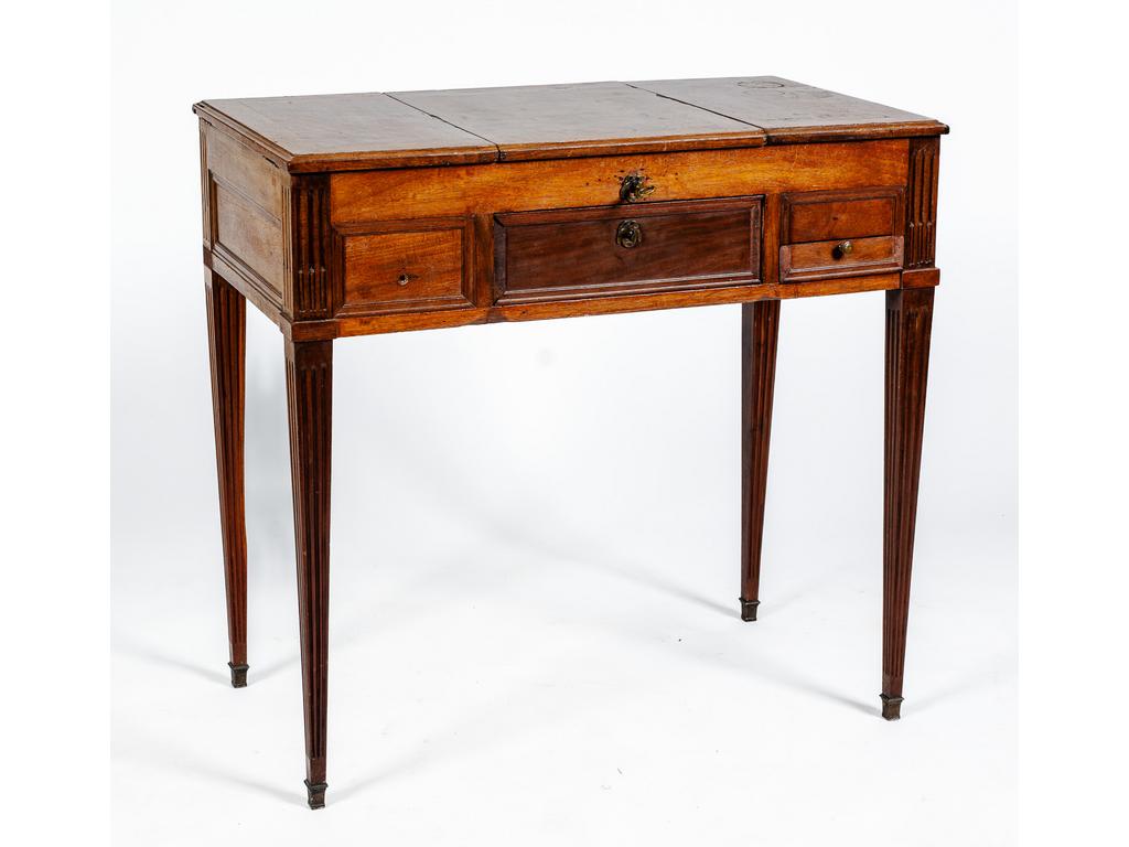 Coiffeuse d'époque Louis XVI en acajou et placage d'acajou ouvrant par deux tiroirs et trois abattants dont un foncé d'une glace et reposant sur quatre pieds cannelés et rudenté.(Manques des poignées de tirages, tâches et accidents). Dim : 75 x 78.8 x 44 cm.