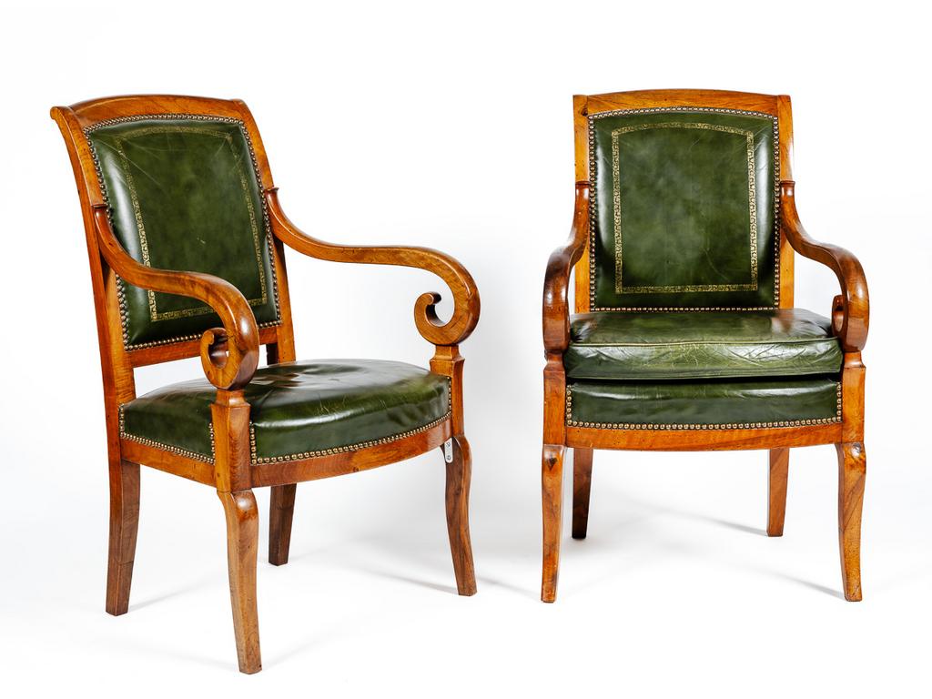 Paire de fauteuils à crosse en acajou et placage d'acajou. Garniture de cuir vert doré au petit fer. (Un avec galette). (Trous de xylophages)