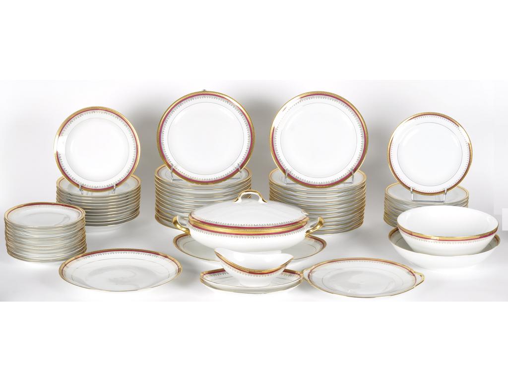 Service de table en porcelaine de Limoges à décor de liserés pourpre et doré comprenant : 26 assiettes plates, 10 petites assiettes, 12 assiettes creuses, 12 assiettes à dessert (avec éclats), une soupière, un plat ovale, deux raviers, une saucière, un saladier, un plat creux, un plat rond et un plat à gâteaux.