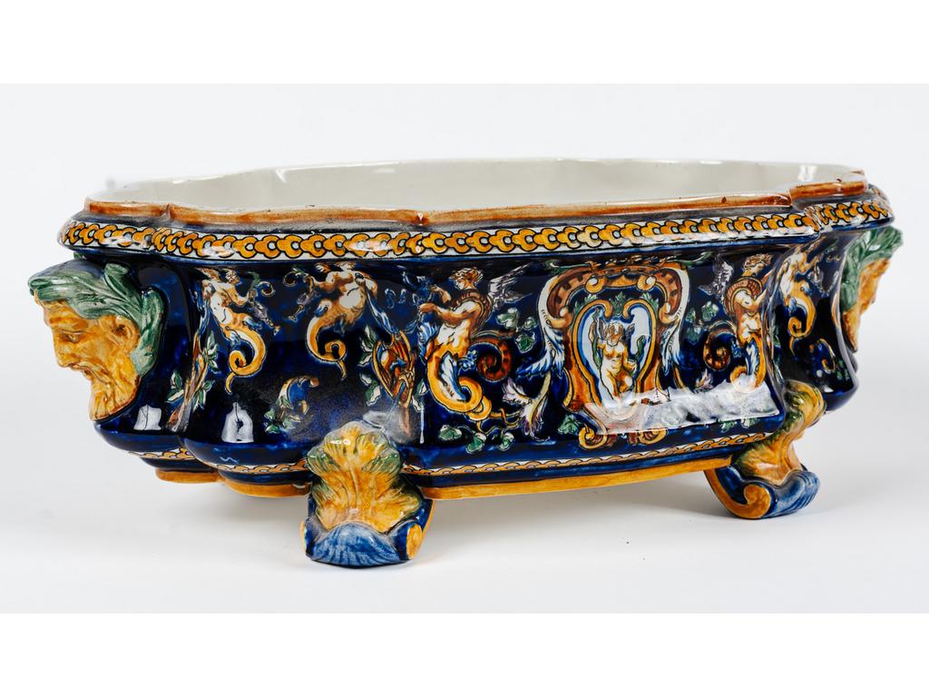 GIEN : Jardinière de table en faïence fine à décor de grotesque et mascarons. Travail Moderne. (Fêles). Dim : 16.5 x 47 x 28 cm.