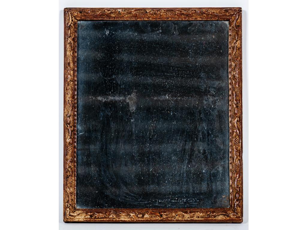 Petit miroir dans un cadre baguette en bois sculpté à la Bérain. Epoque XVIIIème siècle. (Trous de xylophages et dédoré). Dim : 45.5 x 37 cm.
