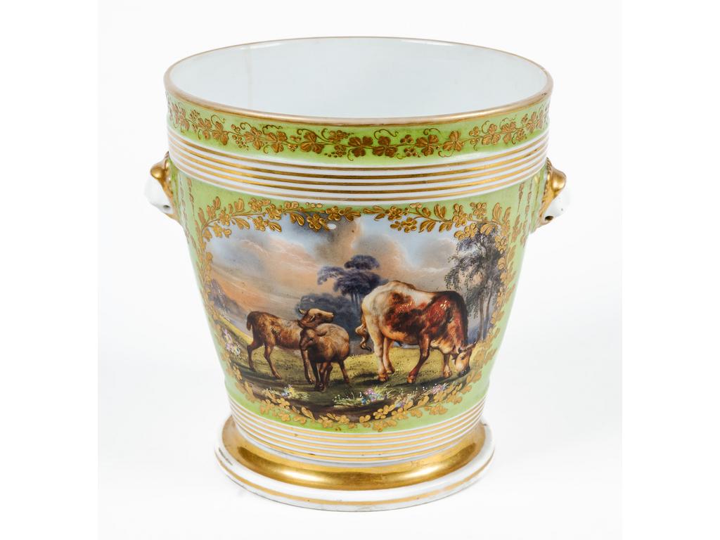 Cache pot en porcelaine de Paris à décor polychrome d'une scène champêtre dans un médaillon en réserve sur fond vert. Hauteur : 20.5 cm. Diamètre : 19 cm