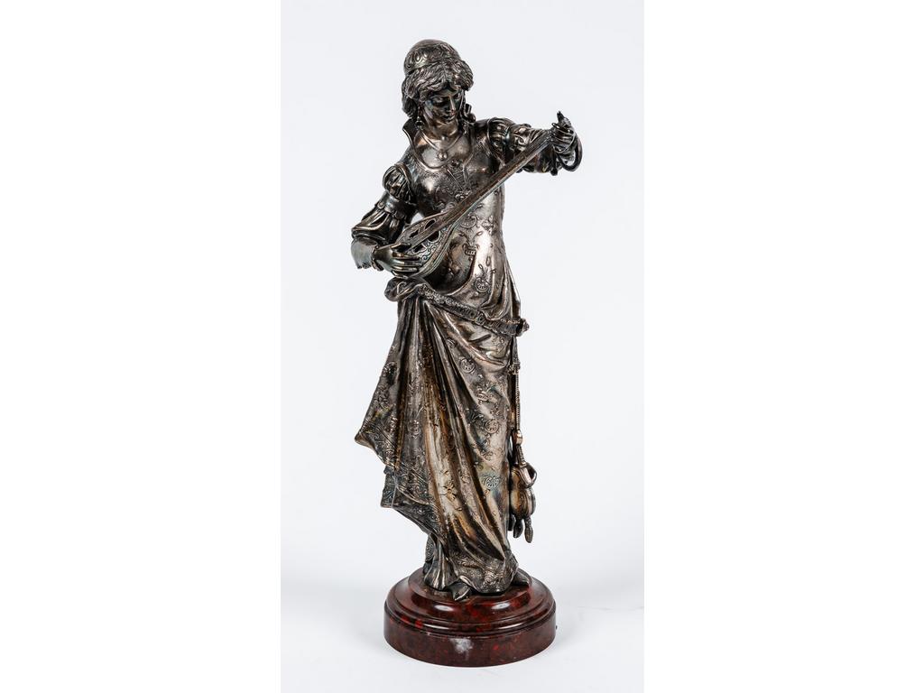 Léon CHEDEVILLE (daprès) : La joueuse de luth. Sujet en cuivre à patine argentée, reposant sur un socle en marbre rouge griotte (accidents et manques). Hauteur totale : 51 cm.