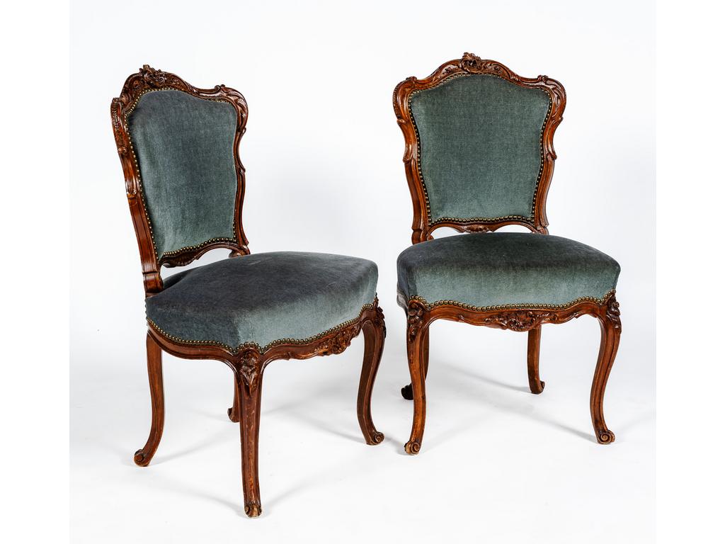 Paire de chaises de style Louis XV en noyer mouluré et sculpté à décor de rocaille, reposant sur quatre pieds cambrés. Garniture de velours.