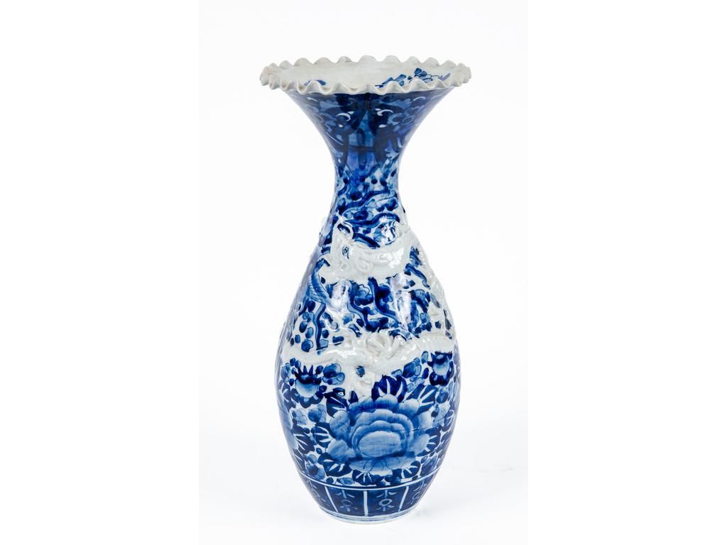 JAPON : Vase balustre en porcelaine à décor en léger relief bleu et blanc d'un dragon sur fond de fleurs. Epoque XXème siècle. Hauteur : 46.5 cm.