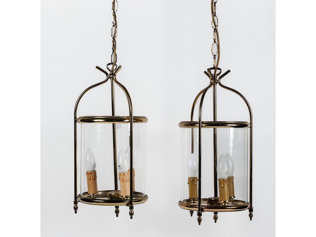 Paire de lanternes de vestibule cylindrique en laiton et verre éclairant par trois bras de lumière. Epoque XXème siècle. Hauteur sans la chaîne : 50 cm.