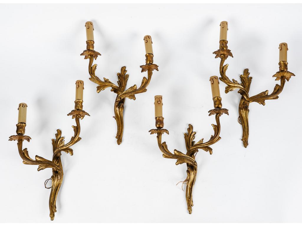 Quatre appliques de style Louis XV à deux bras de lumière de style Louis XV en bronze et laiton doré à décor de feuillages. (Montés à l'électricité). Hauteur : 41 cm.