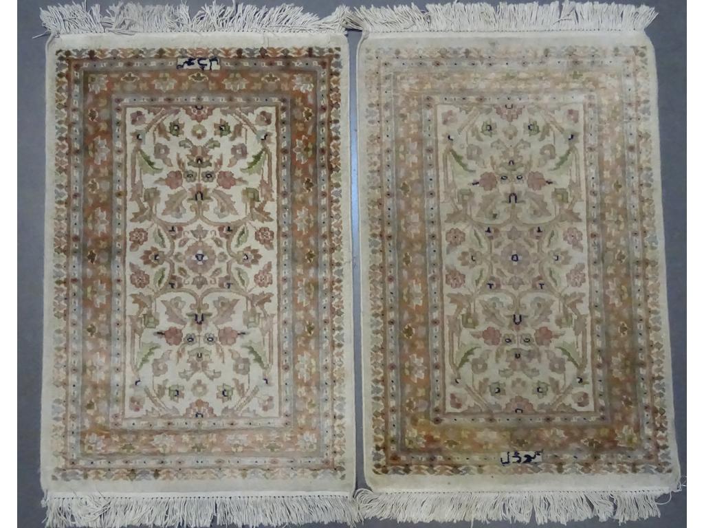 PAKISTAN : Deux petits tapis en laine et soie à décor de végétaux stylisés sur fond ivoire. (Un tâché). Dim : 106 x 62 cm.