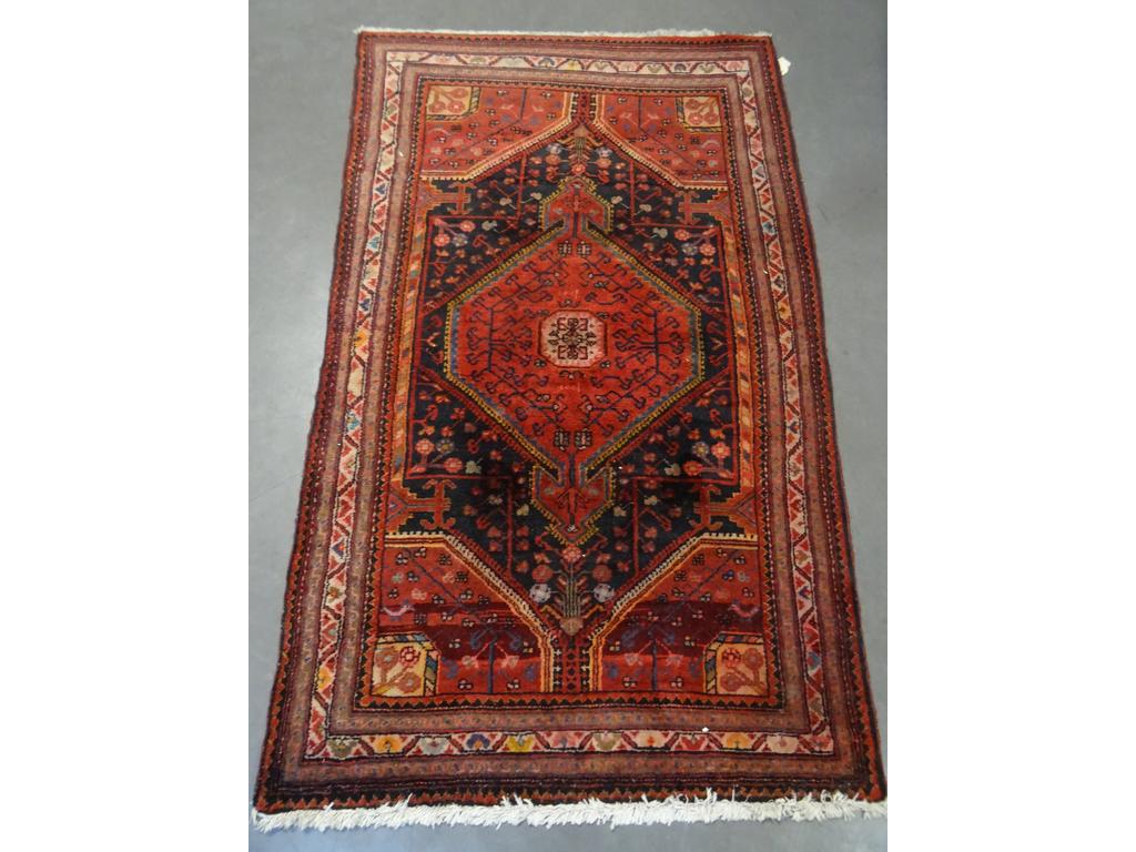 IRAN : Un tapis en laine à décor de médaillon central. Bon état. Dim : 192 x 116 cm.