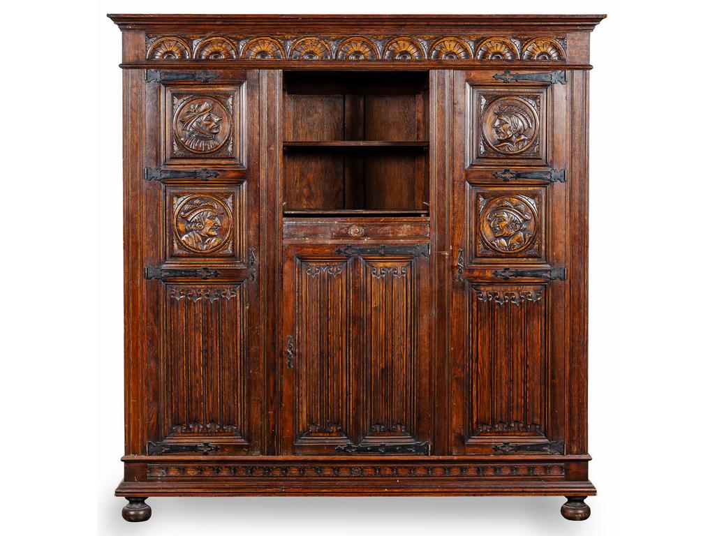 Armoire en chêne de style Renaissance richement sculptée de portraits et plis de serviette. Elle ouvre par trois portes encadrant une niche. (Corniche restaurée). Dim : 189.5 x 184 x 50 cm.