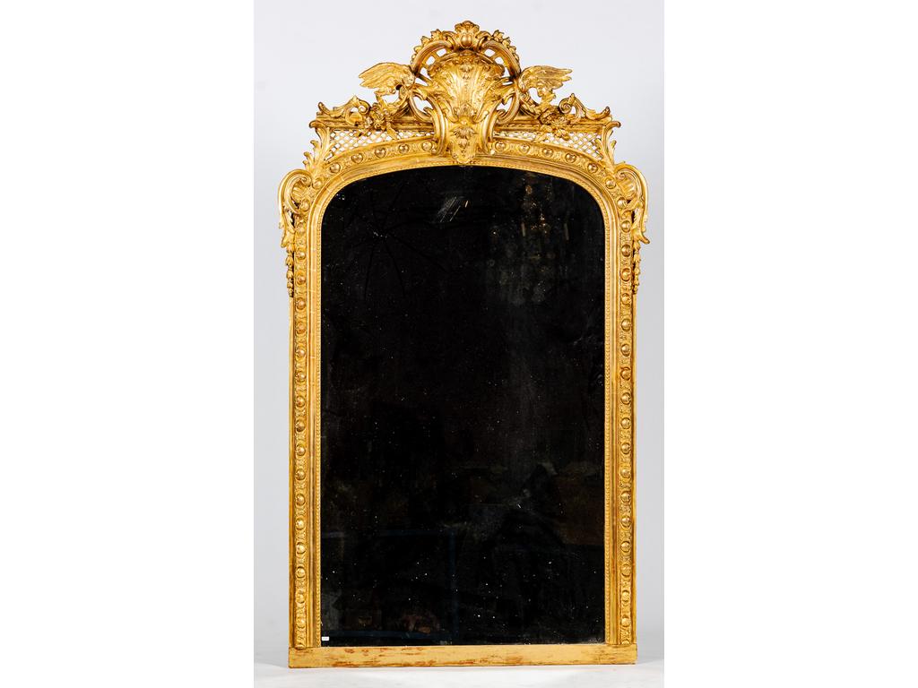 Important miroir à fronton en bois et stuc doré richement orné de rinceaux feuillagés, fleurs, panaches et treillages. Epoque fin XIXème siècle. (Reprises à la dorure et restaurations). Dim : 198 x 114 cm.