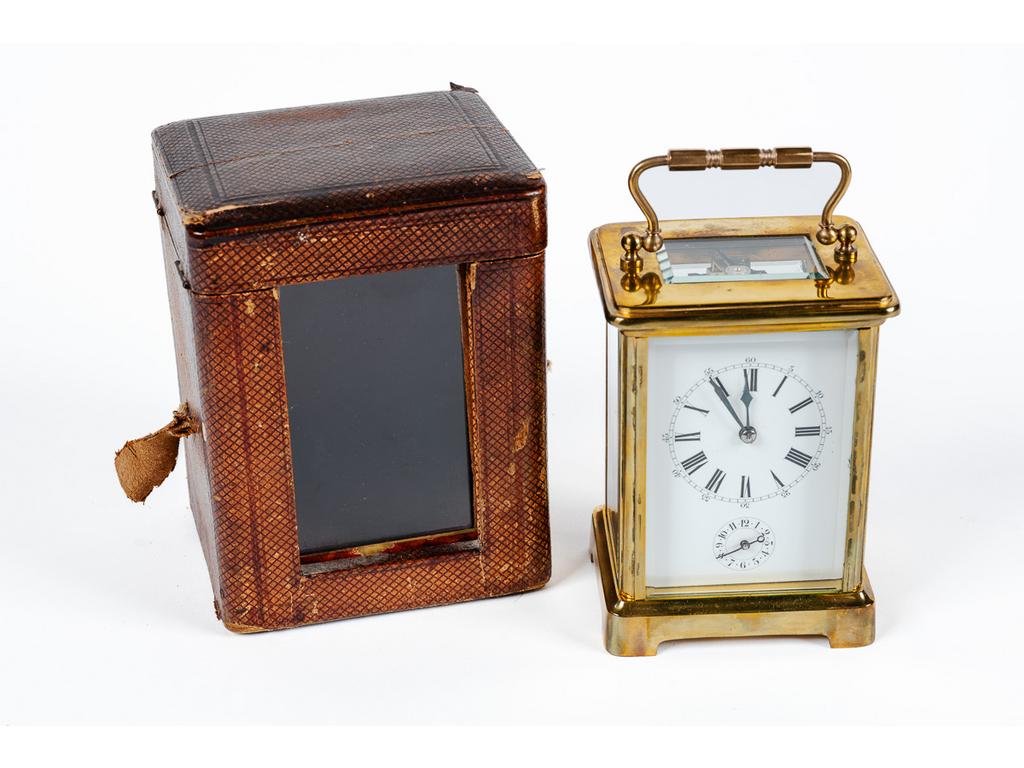 Pendulette d'officier en laiton et verre dans son coffret gainé de cuir. (Usures au coffret et déchirures, mécanisme à réviser, vitre arrière avec accident). Dim : 11.5 x 8 x 6.5 cm.
