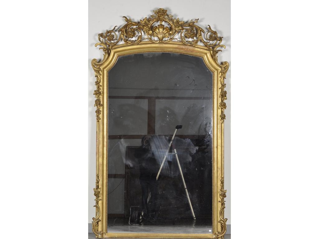 Grand miroir en stuc doré en partie redoré. La partie haute en forme de chapeau de gendarme orné de rinceaux, coquille et fleurs ajourés. (Quelques petites parties en stuc abîmées). Epoque Napoléons III. Dim : 235 x 142 cm.