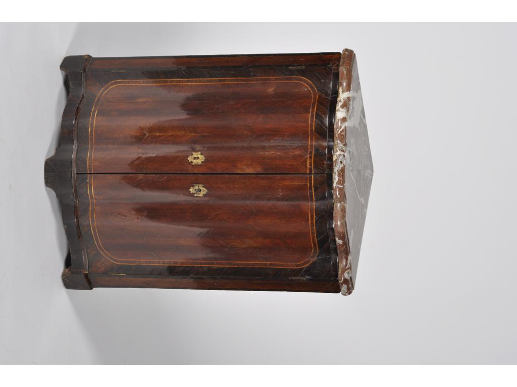 Petite encoignure en bois de placage marqueté ouvrant par deux portes sur une façade joliment galbée surlignée de filets de bois clair. Plateau en marbres rouge de France. Epoque XVIIIème siècle. (Manques et restaurations au placage). Hauteur : 79 cm, côté : 44 cm.