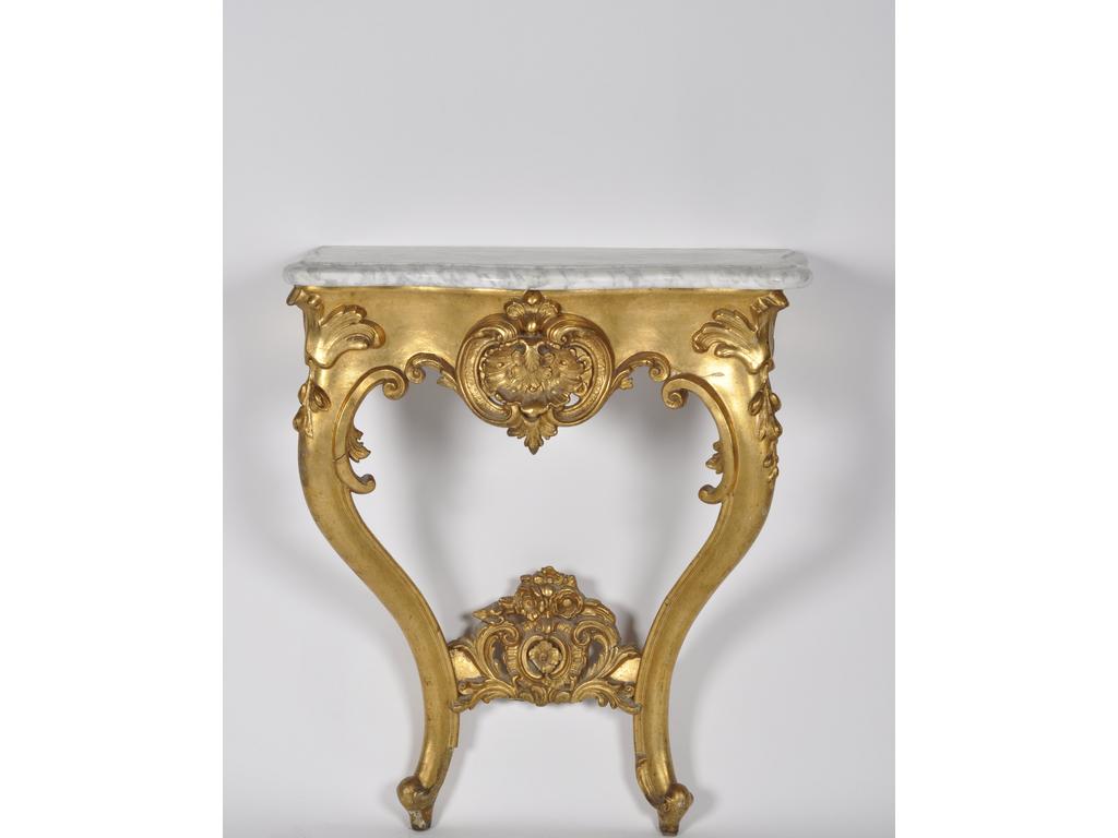 Petite console de style Louis XV en bois redoré. Ceinture ajourée d'une coquille reposant sur deux pieds cambrés reliés par un motif sculpté de fleurs. Plateau de marbre blanc. (Manques au sabot du pieds gauche et petits accidents). Dim : 83 x 73 x32 cm.