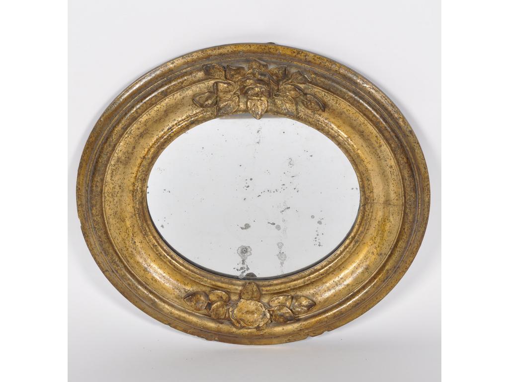 Petit miroir médaillon de forme ovale en bois sculpté et redoré orné de deux bouquets de fleurs (1 bouquet abîmé avec manques). Dim : 49 x 43 cm.