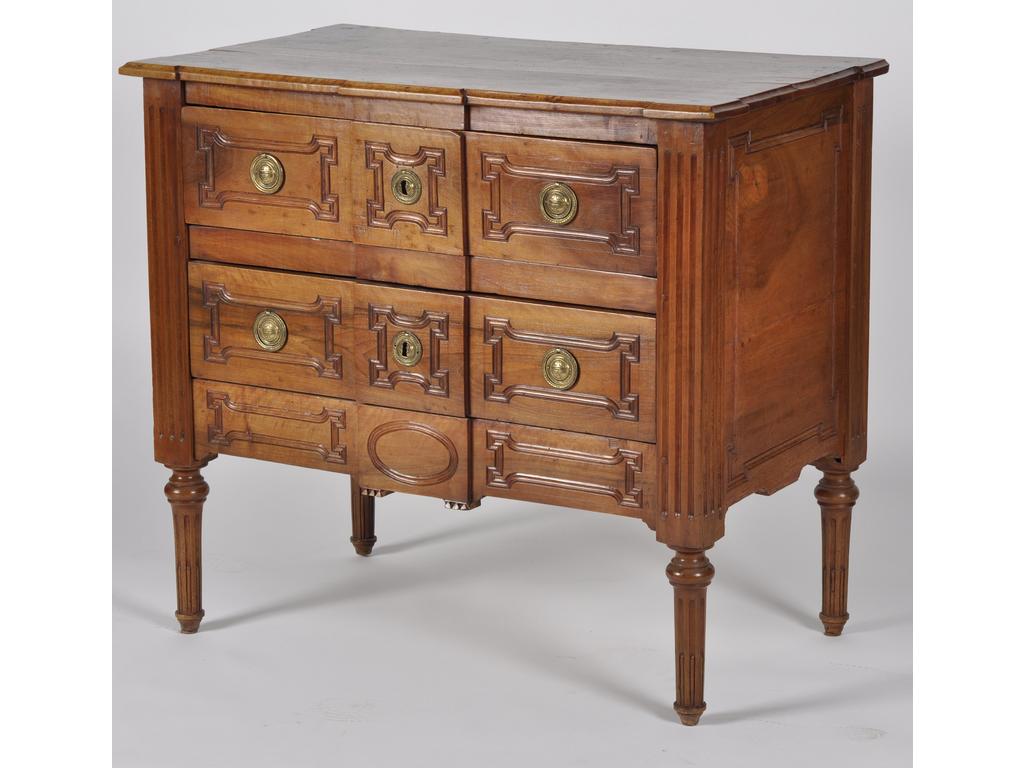 Commode provençale d'époque Louis XVI en noyer sculpté. Elle ouvre sur une façade à ressaut central par deux tiroirs. Les quatre montants cannelés reposant sur des pieds fuselés. Plateau en noyer (tâché). (Fond restauré). Dim : 92 x 103 x 58 cm.
