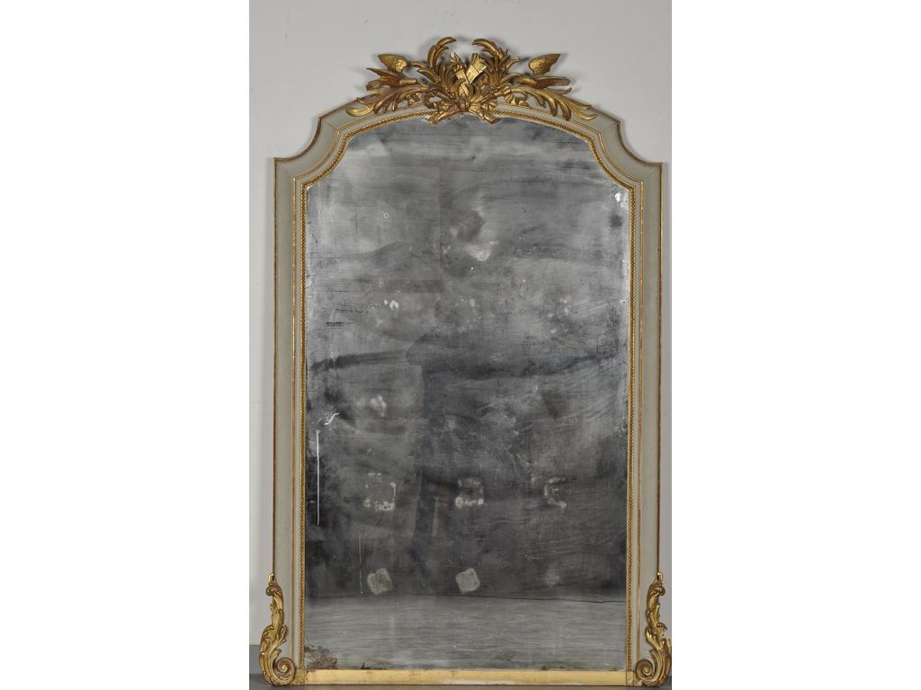 Grand miroir de style Louis XVI en bois relaqué gris et doré. Partie supérieure en forme de chapeau de gendarme orné d'un trophée de carquois, torche, palme et deux oiseaux. Epoque fin XIXème siècle. (Tain du miroir abîmé dans l'angle inférieur gauche). Dim : 216 x 130 cm.