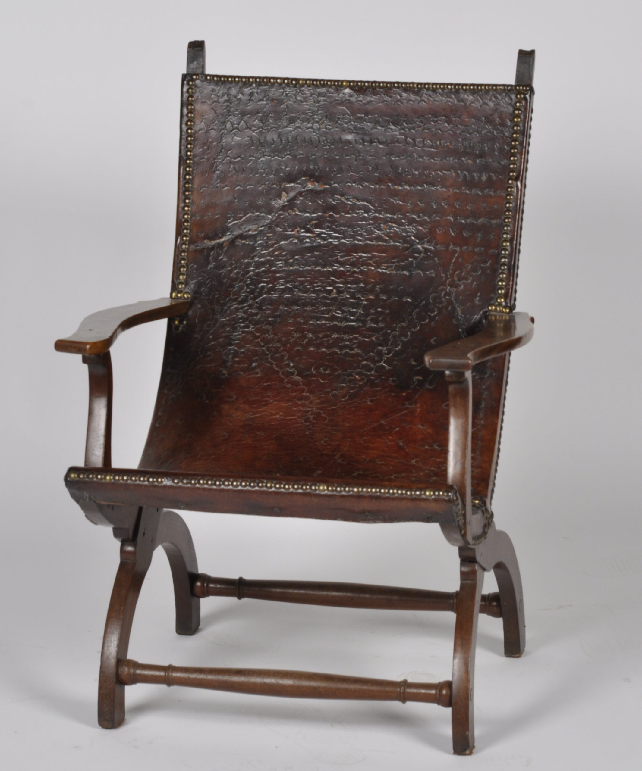 Fauteuil en noyer garni de cuir clouté et reposant sur un piètement en X à entretoise. Epoque XIXème. (Usure au cuir).