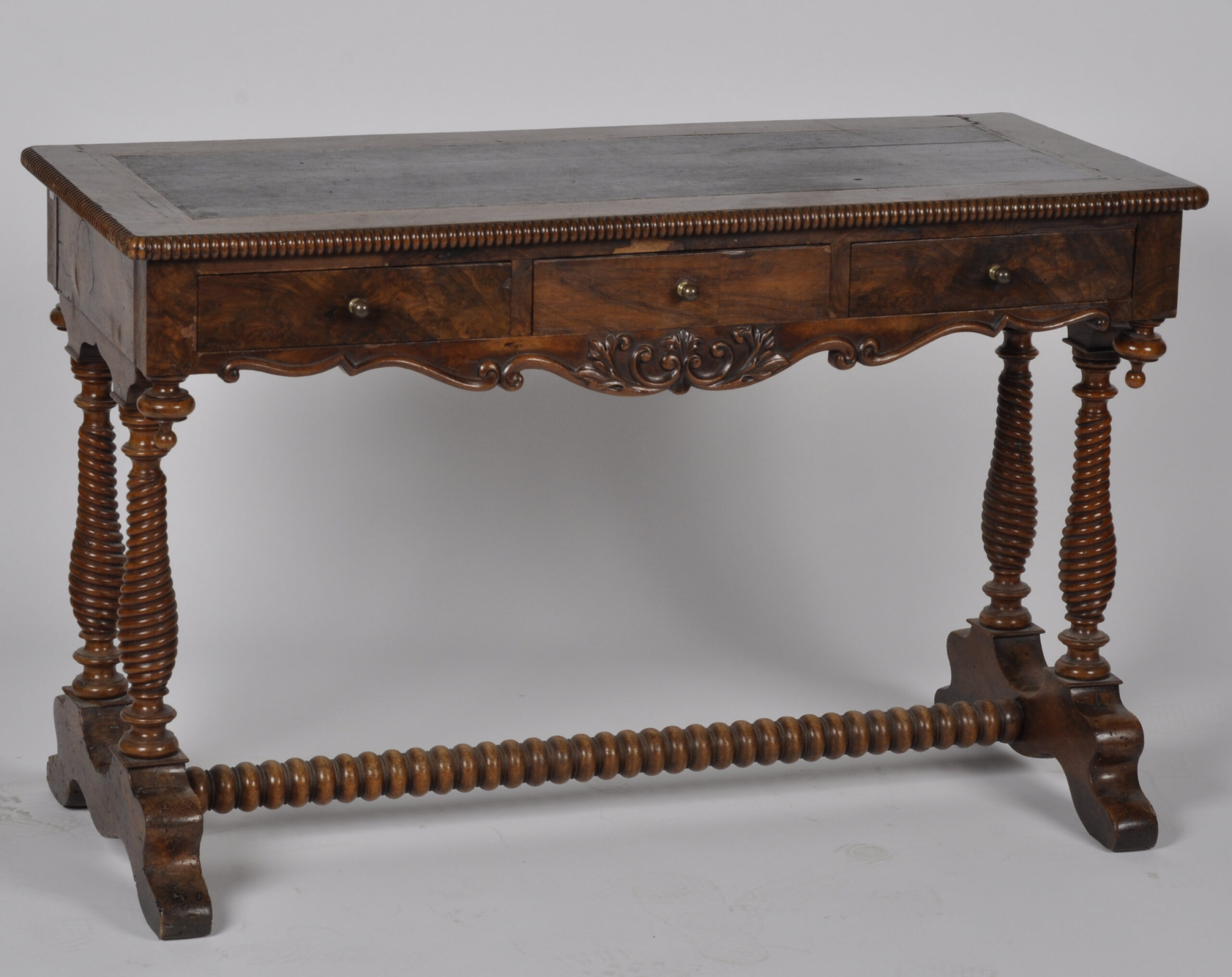 Table à écrire en acajou et placage d'acajou ouvrant par trois tiroirs en ceinture et reposant sur quatre pieds tournés réunis par une entretoise. Époque XIXème siècle (reprises au placages) Dim: 72 x 114 x 52 cm Piétement tourné et plateau gainé de cuir.