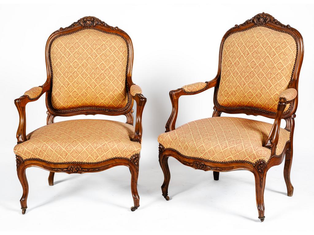 Paire de fauteuils à dossier plat de style Louis XV en noyer mouluré et sculpté à décor de fleurs, feuillages et coquilles. Garniture de tissus.