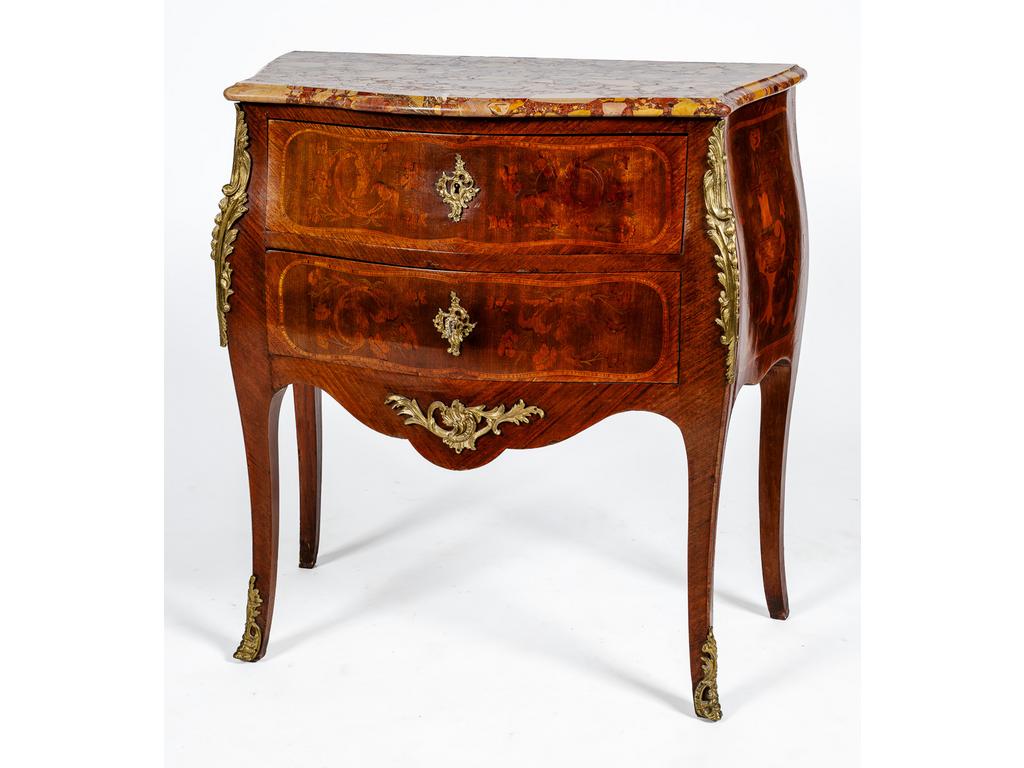 Petite commode toutes faces galbées de style Louis XV en bois de placage à décor marqueté de vases et rinceaux fleuris. Elle ouvre par deux tiroirs et repose sur quatre petits pieds cambrés. Garniture de laiton. Plateau de marbre brèche (un angle cassé). Dim : 85 x 79 x 43 cm.