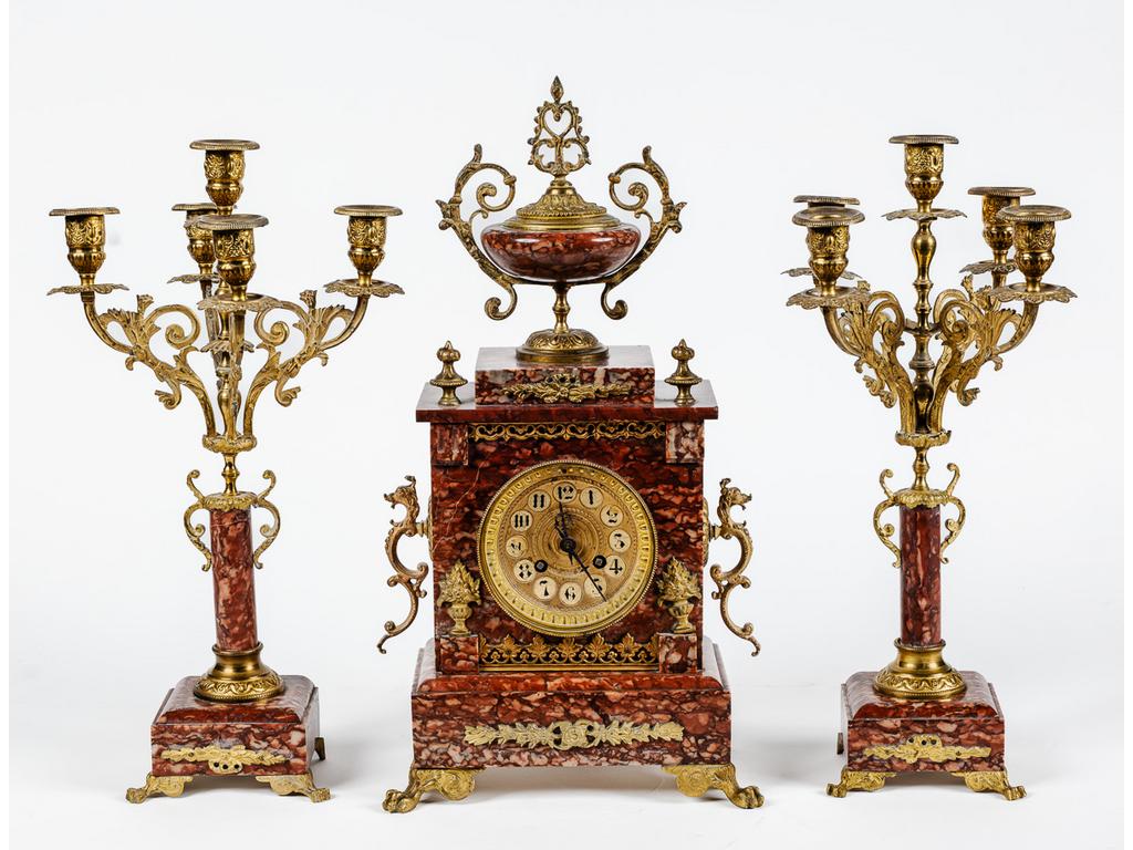 Garniture de cheminée en marbre rouge, laiton et bronze comprenant une pendule surmontée d'une urne à anses et une paire de candélabres à cinq bras de lumière. Epoque fin XIXème siècle.(Sans balancier). Dim pendule : 46 x 24 x 11 cm.