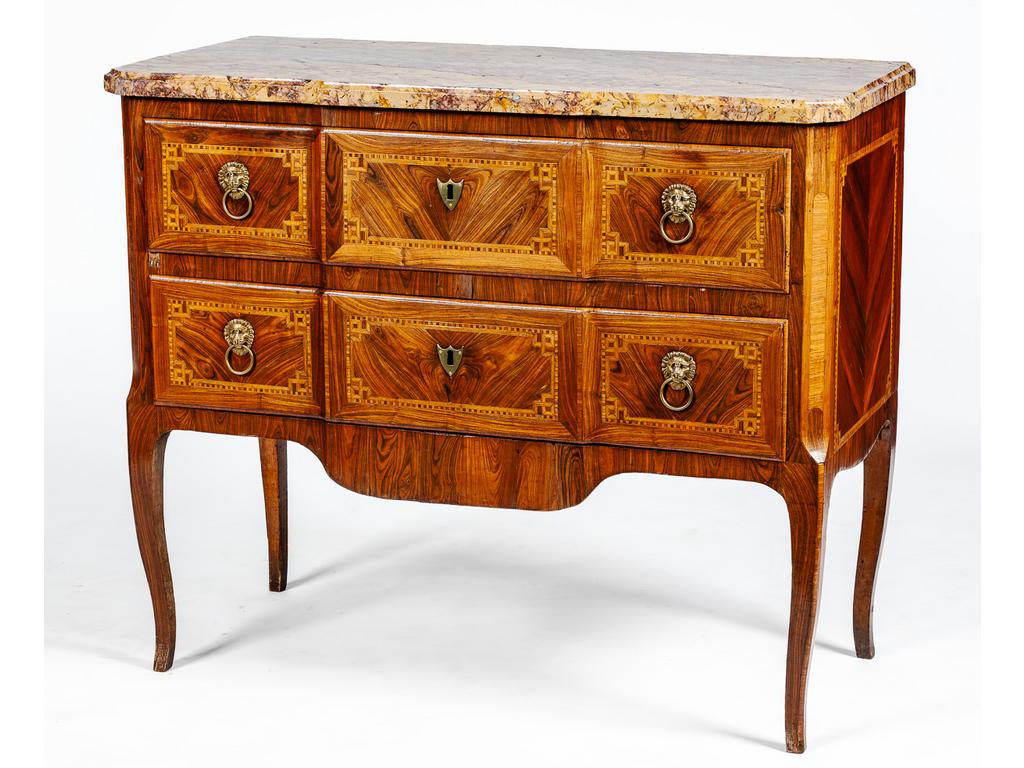 Commode à ressaut central d'époque Transition Louis XV - Louis XVI en bois de placage et à décor marqueté de grecque et filets, reposant sur quatre petits pieds cambrés. Elle ouvre par deux tiroirs ornés de poignées de tirages en bronze figurant des mufles de lion. Plateau de marbre reposant sur des montants antérieurs à pans coupés. (Petits manques au placage et restaurations des fonçures de la caisse). Dim : 92 x 112 x 50 cm.