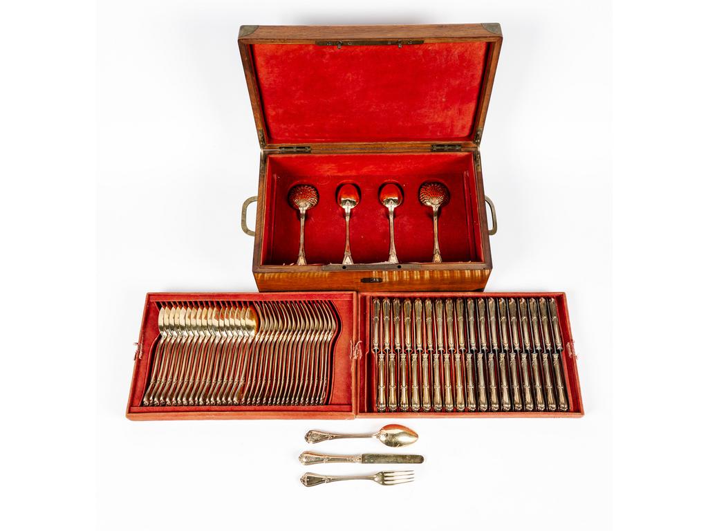 COSSON-CORBY : Dans son coffret en acajou, une ménagère en vermeil comprenant 18 couverts à entremets monogrammés, 36 couteaux (18 lames vermeil , 18 lames acier), 2 saupoudreuses et deux cuillères de service. Poids net (sans les couteaux) : 2 152 gr.