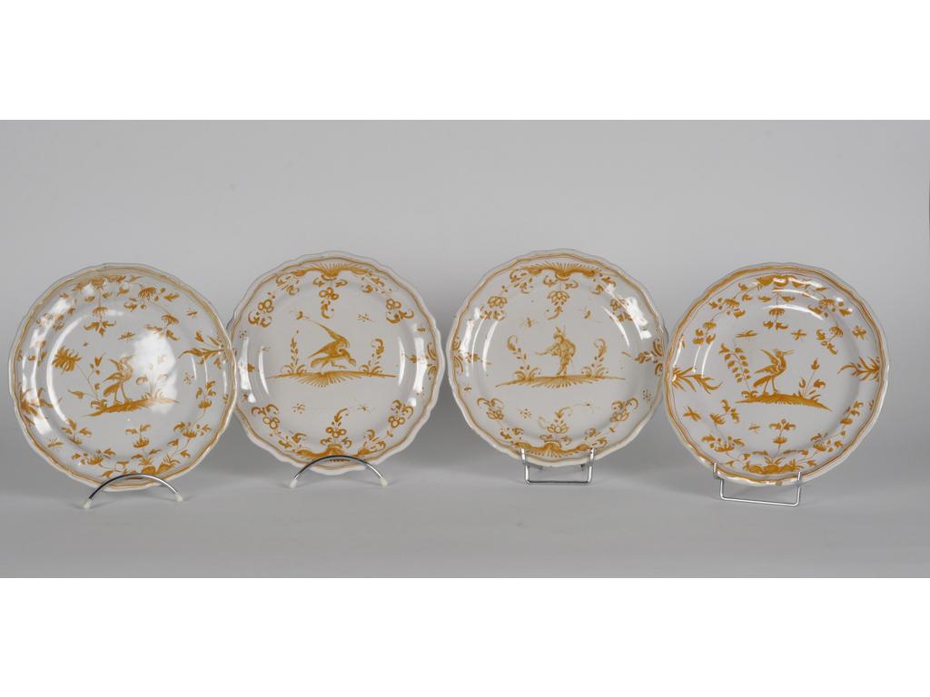 MOUSTIERS : Quatre assiettes en faïence émaillée à décor en camaïeu jaune d'oiseaux et grotesques sur des tertres. Epoque fin XVIIIème siècle. (Une avec fêle, une avec cheveu dans l'émail et une avec petit éclat). Diamètre : 25 cm.