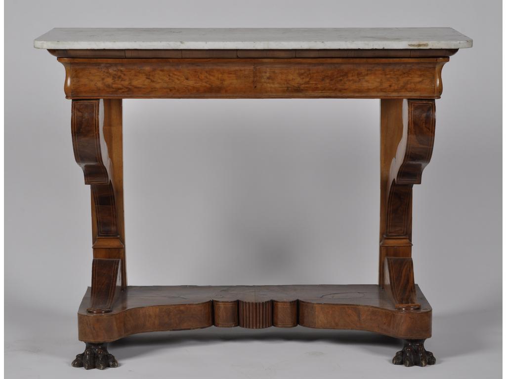 Console d'époque Restauration en placage de noyer orné de filets marquetés en bois clair. Elle ouvre par un tiroir en ceinture et repose sur deux pieds griffe. Plateau de marbre blanc. (Fêle et éclats au marbre, renfort à l'arrière). Dim : 95 x 122 x 56 cm.