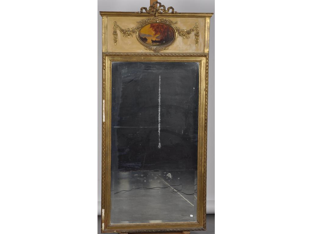 Trumeau de style Louis XVI en bois et stuc doré composé d'un miroir biseauté et surmonté d'un médaillon peint à décor d'un paysage lacustre. Epoque 1900. (Sauts de stuc et dorure). Dim : 168 x 83 cm.