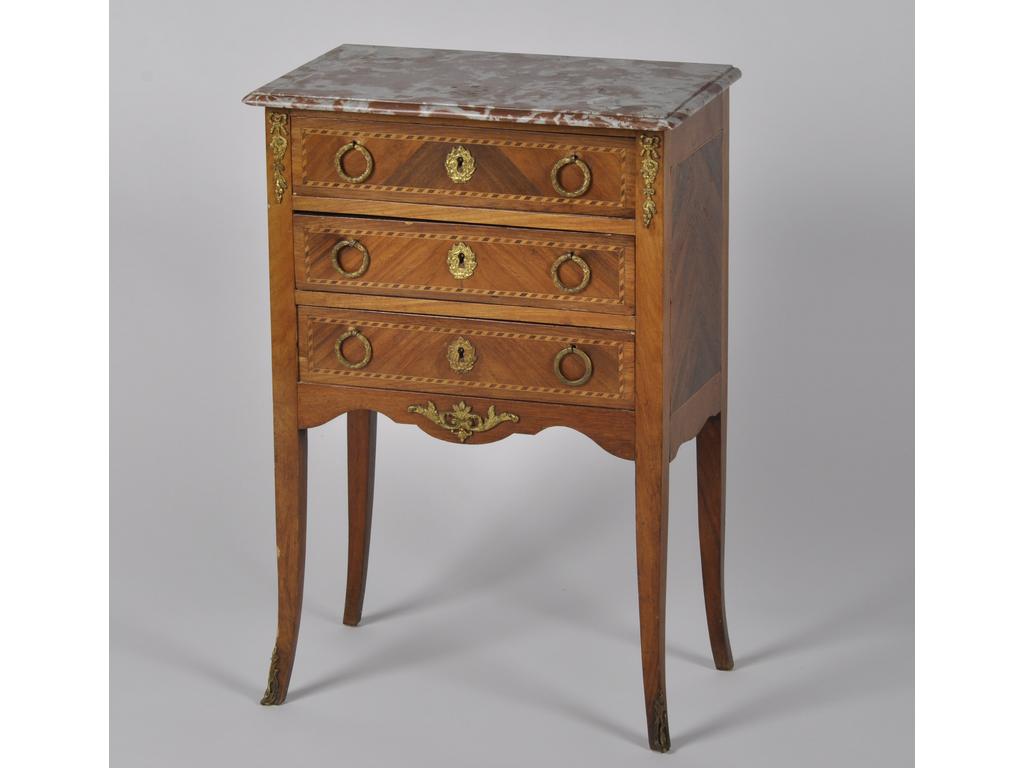 Chiffonière de style Louis XVI en bois de placage et marqueterie ouvrant  par trois tiroirs. Plateau de marbre. Epoque début du XXème siècle. (Petit choc à un pied). Dim : 80 x 54 x 33 cm.